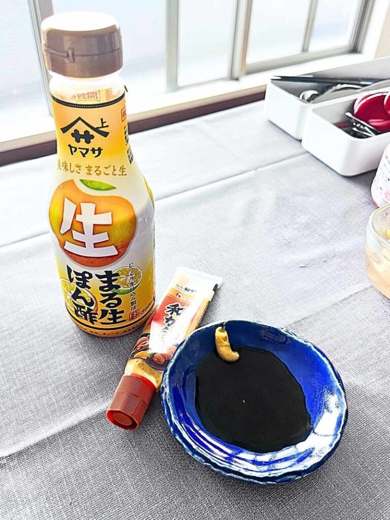 A bottle of ponzu, a tube of karashi mustard and a small blue dish of dipping sauce for gyoza