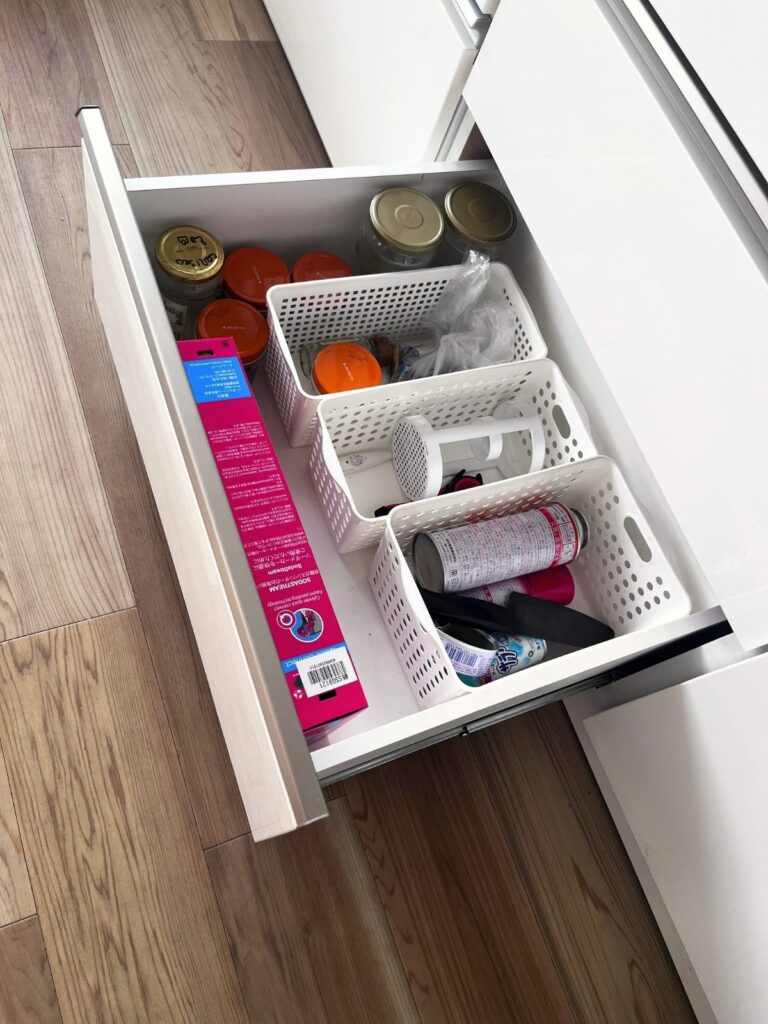 White baskets in the bottom kitchen drawer holding items that are recycled only occasionally