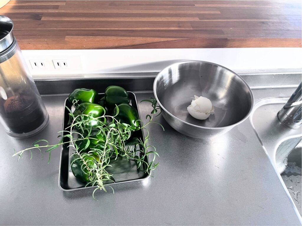 A stainless steel mixing bowl used to collect food scraps while cooking