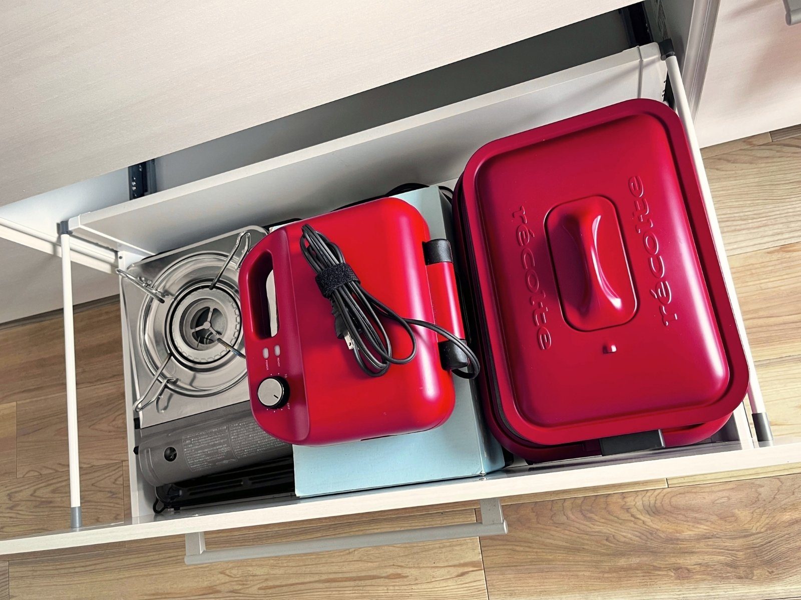 A drawer holding a portable butane stove, a waffle maker and a hot plate