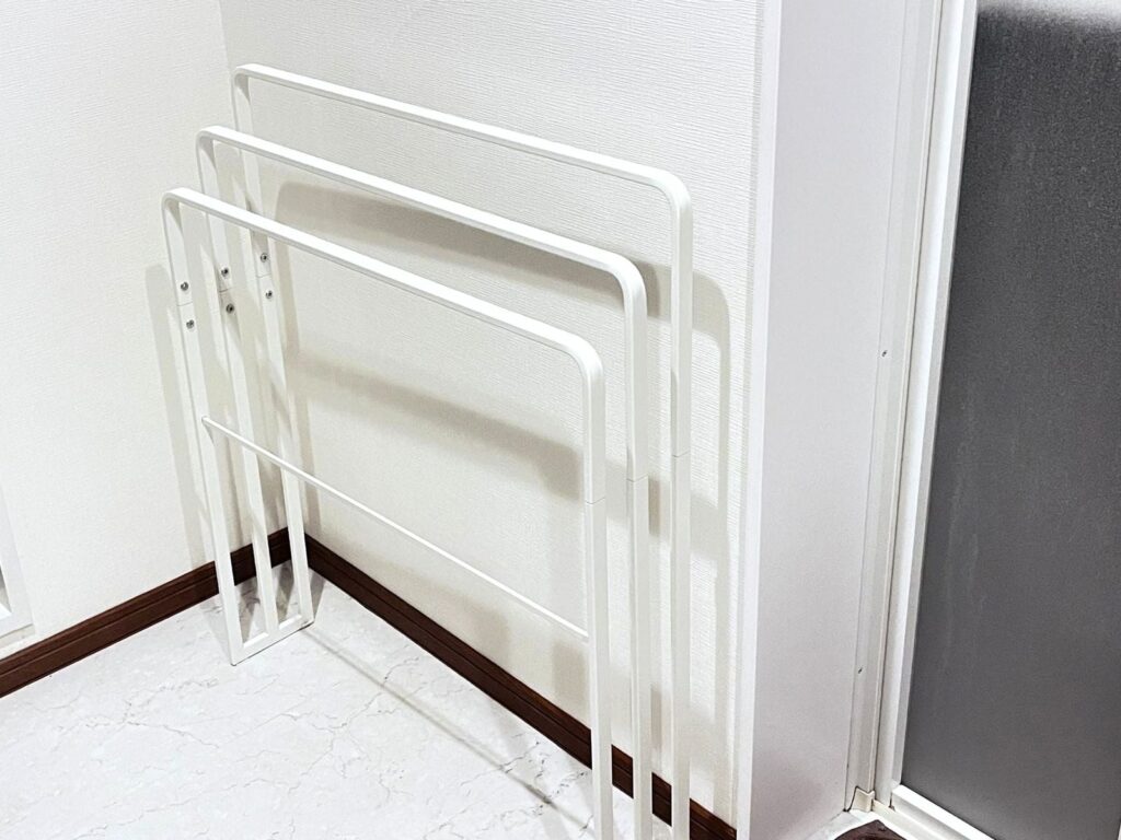 A white freestanding towel stand seen at an angle, showing four bars at different heights