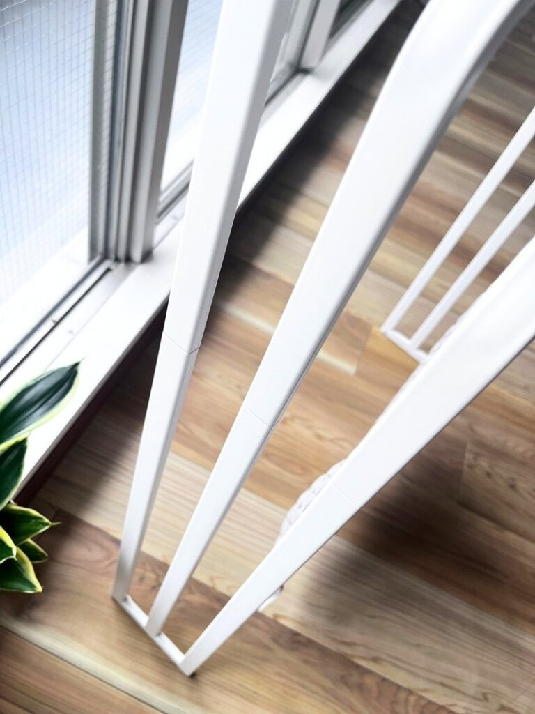 The slim white frame of the towel stand seen from the side
