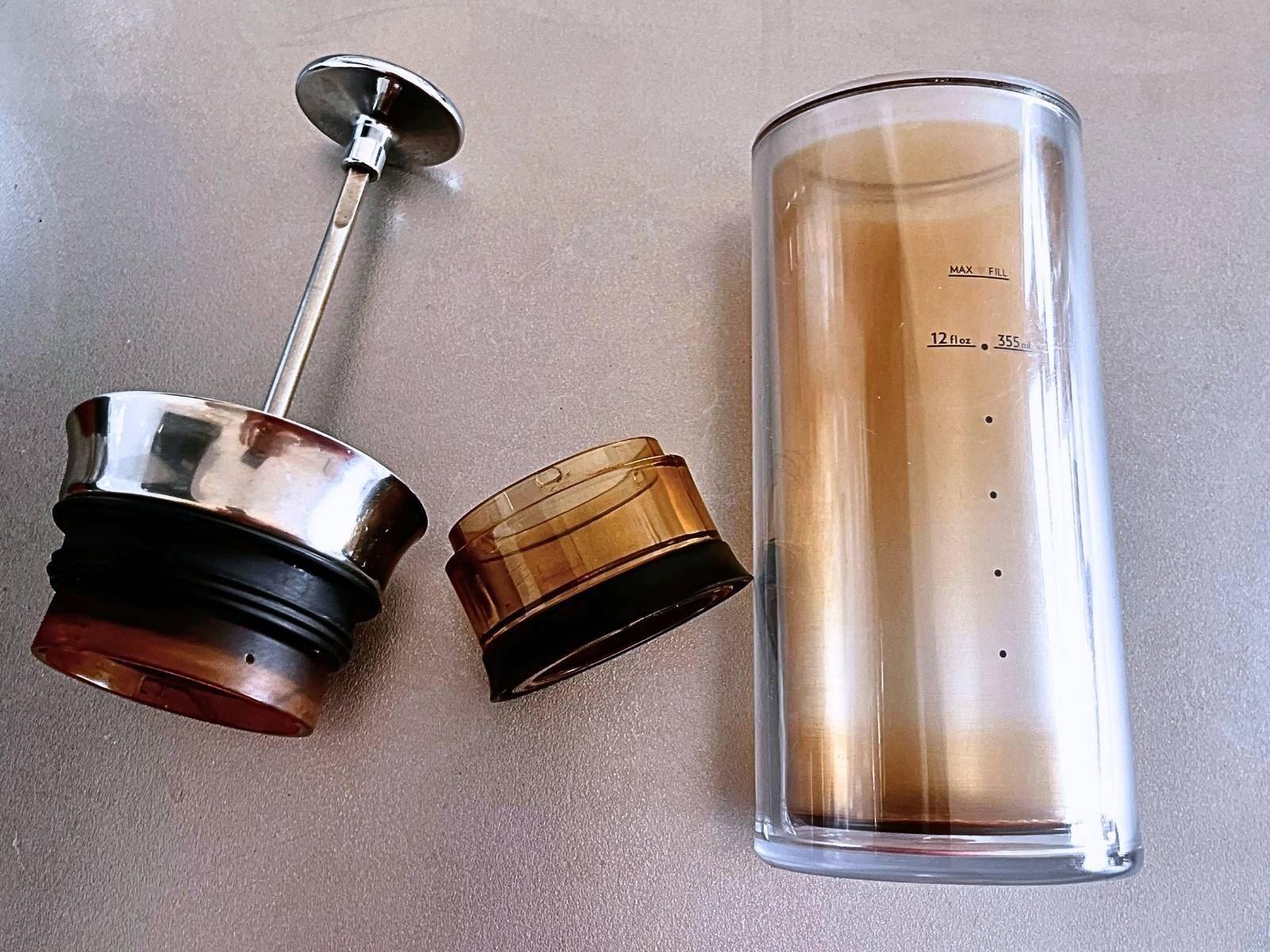 American Press coffee maker taken apart on a kitchen counter, with the plunger and pod next to the clear carafe