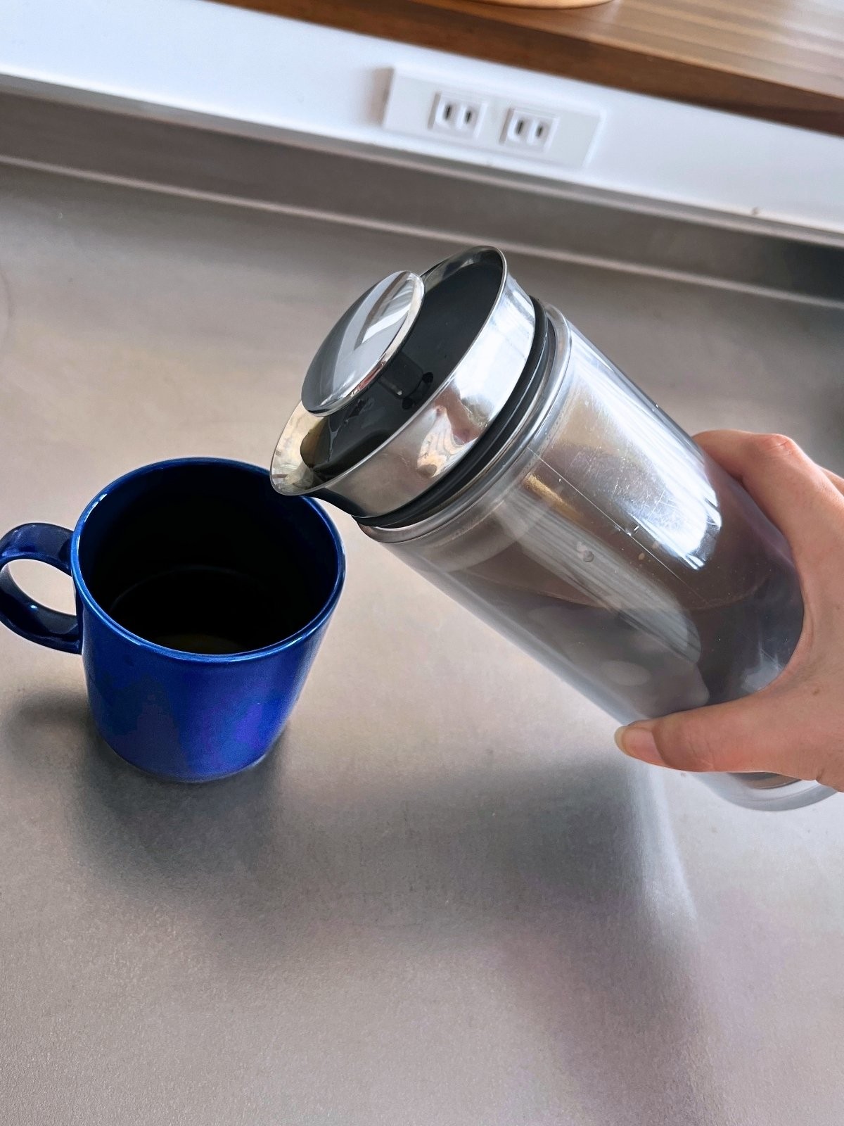Pouring coffee from the American Press into a navy mug