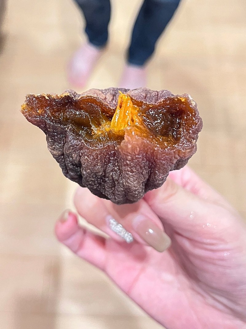 A dried persimmon torn open to show the soft, jelly-like center