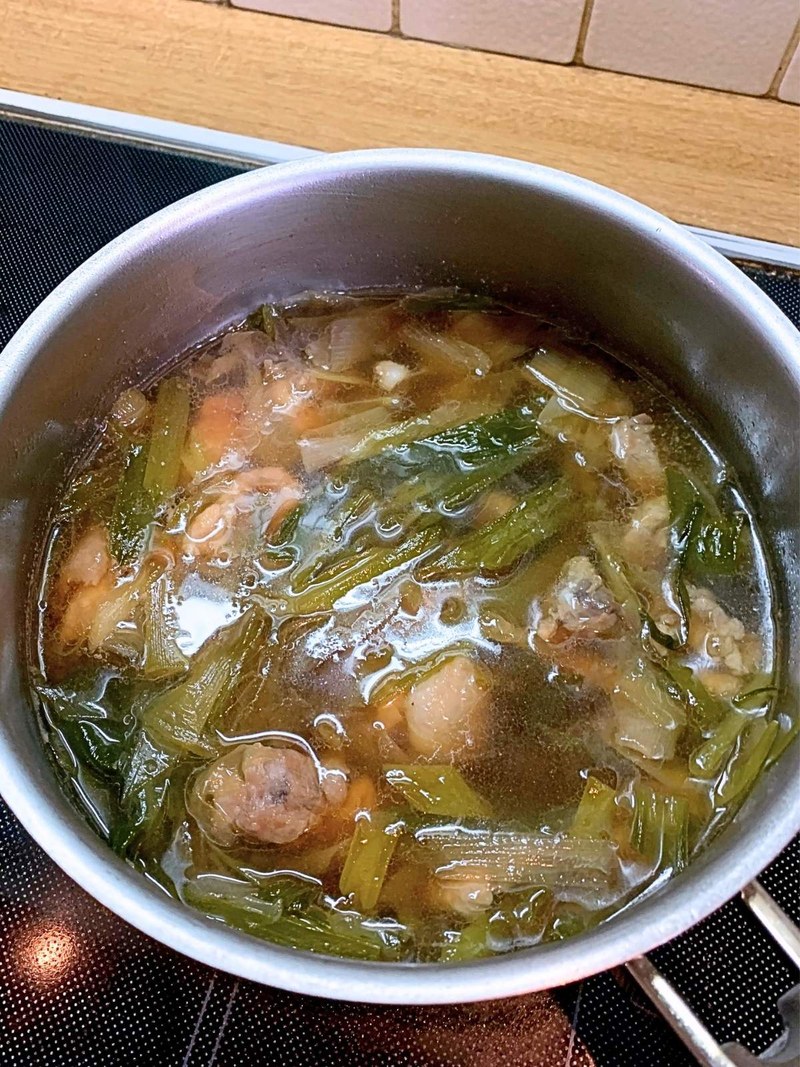 Chicken and leeks simmering in soba broth in a pot