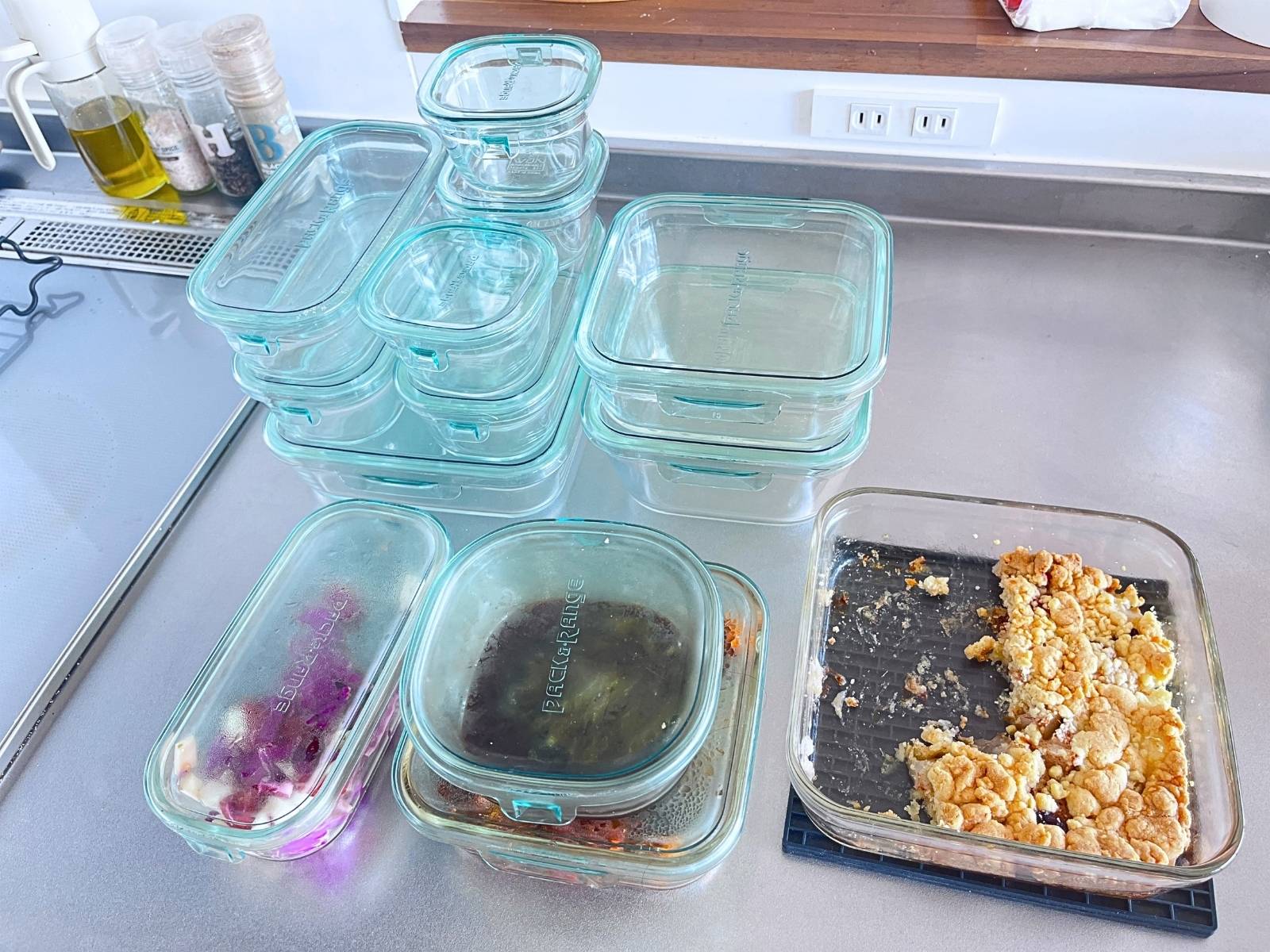 iwaki glass food containers in several sizes on a kitchen counter, with a fruit crumble baked in a square iwaki container