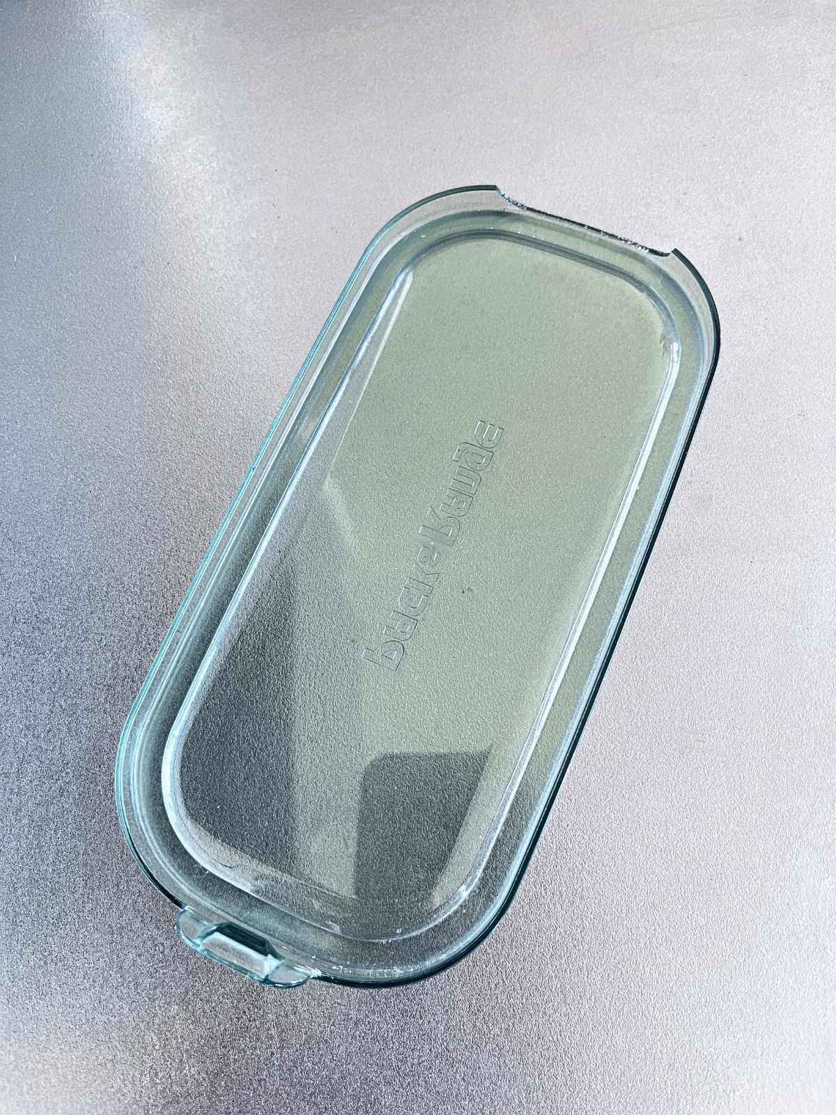 A green-tinted iwaki plastic lid with a chipped corner