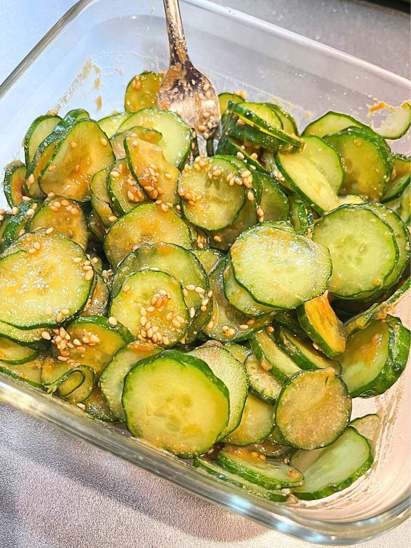 Sesame miso cucumber with sesame seeds in a square glass container, with a fork