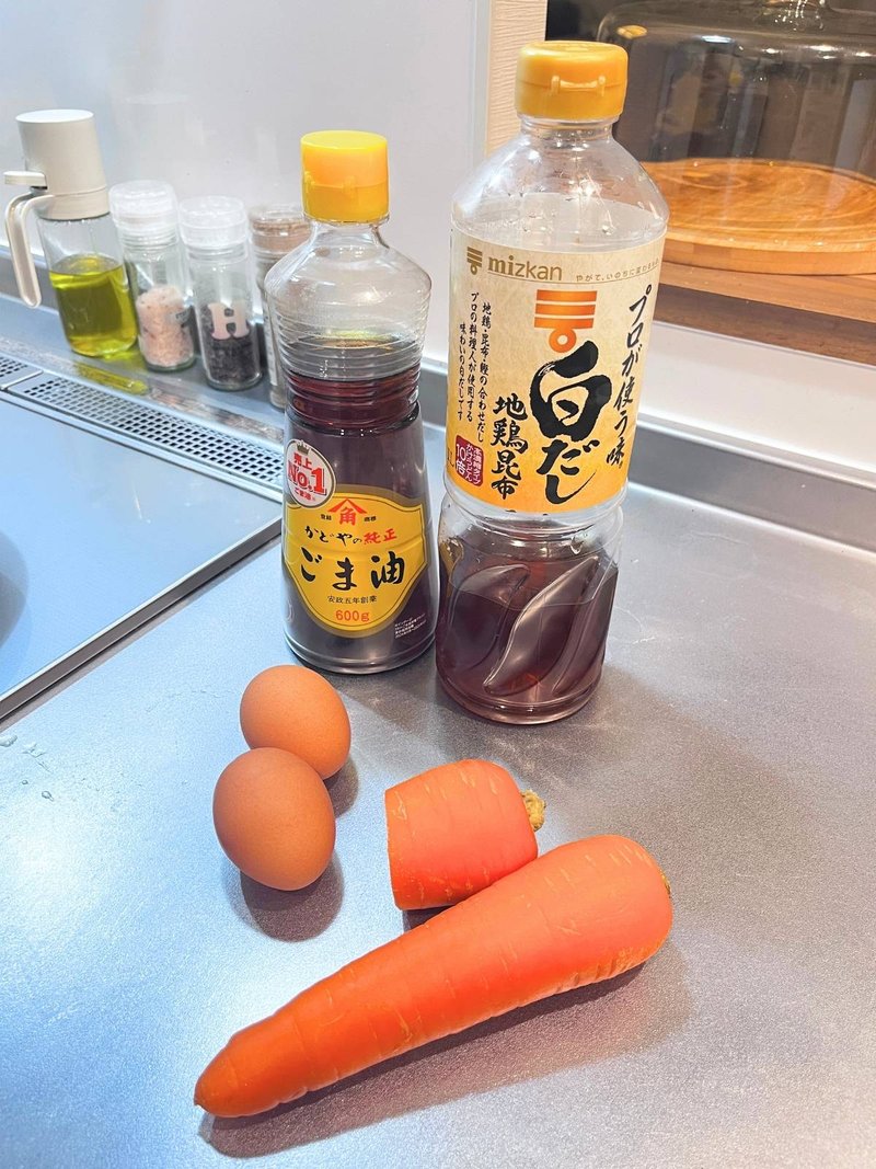 Eggs, carrots, a bottle of shiro dashi and a bottle of sesame oil on a kitchen counter