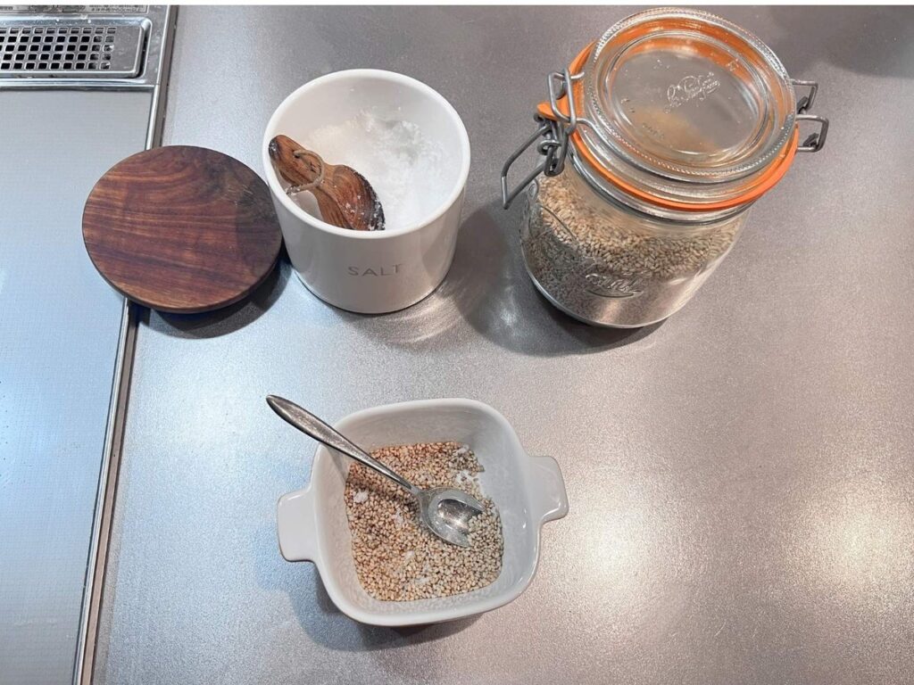 Mixing toasted white sesame seeds and fine salt in a small dish, with a salt cellar and a glass jar of sesame seeds
