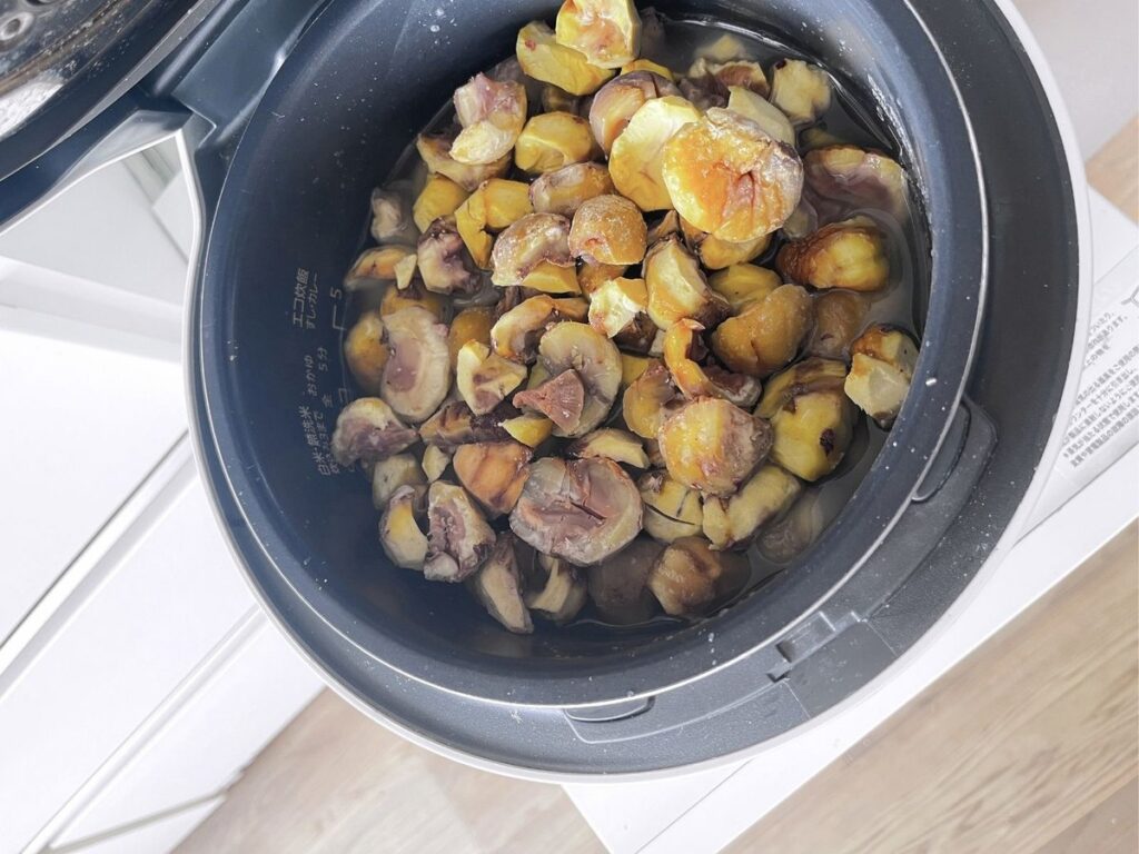 Peeled chestnuts piled on top of rice in a rice cooker pot