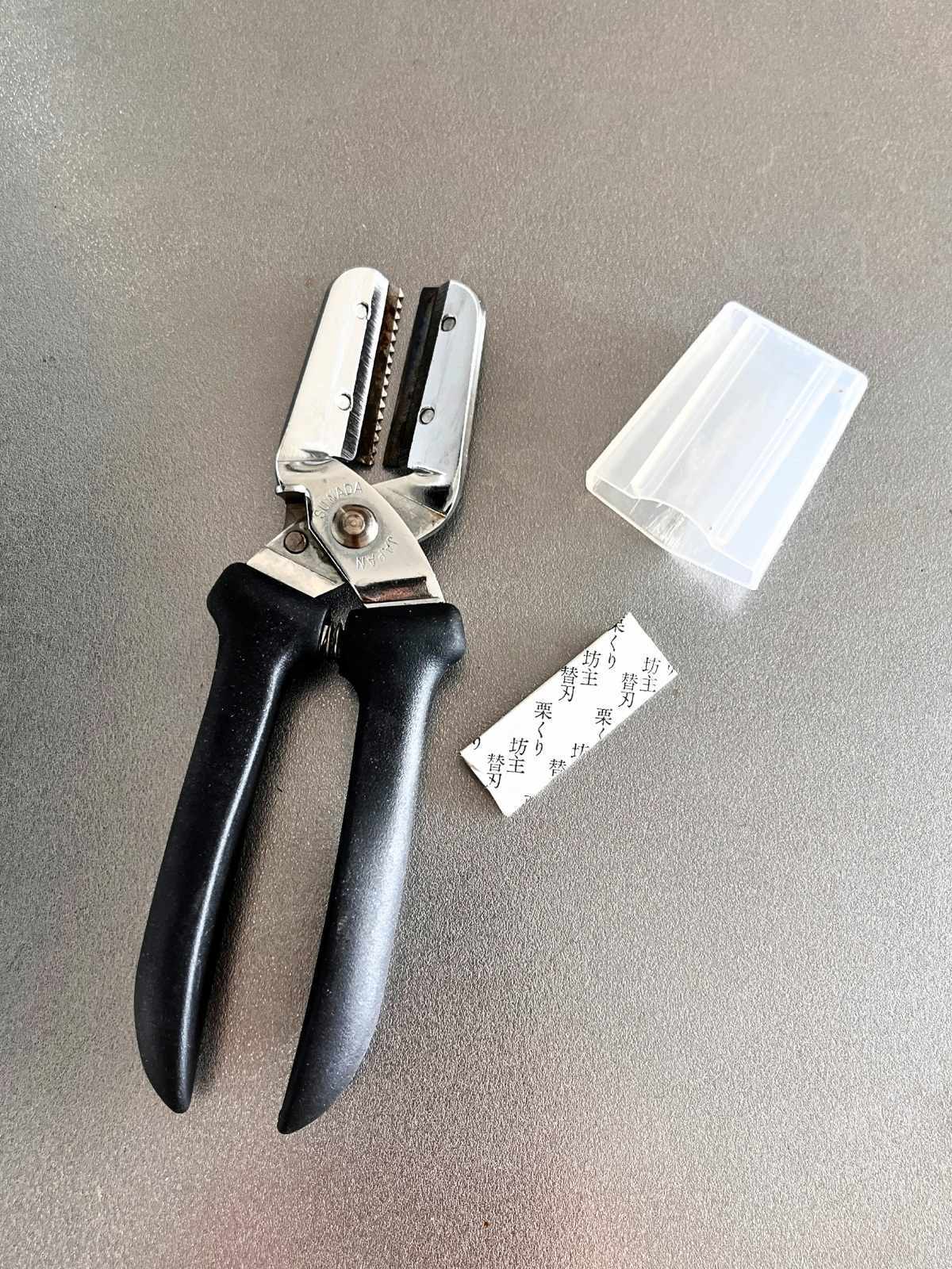 My Suwada Kurikuri Bozu chestnut peeler with its clear cap and a spare blade wrapped in paper