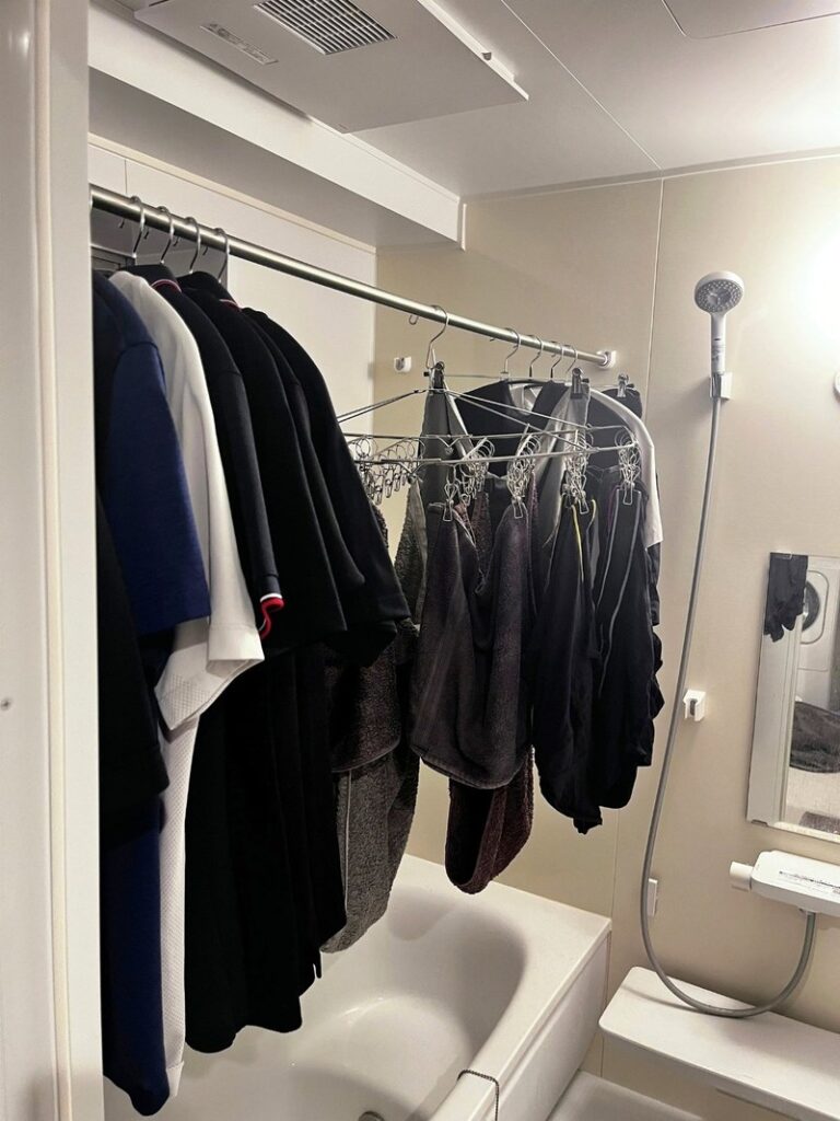 Shirts on hangers and towels on a pinch hanger, drying on the built-in pipe in a bathing room under the ceiling dryer