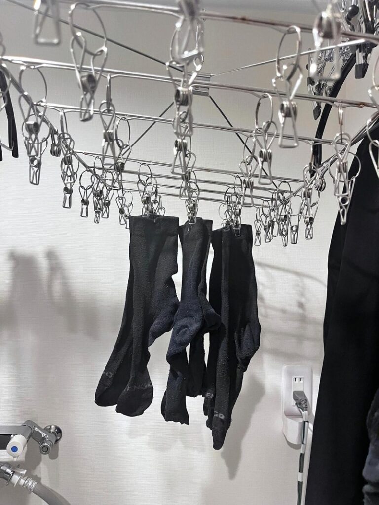 Black socks clipped to a stainless pinch hanger above the washer