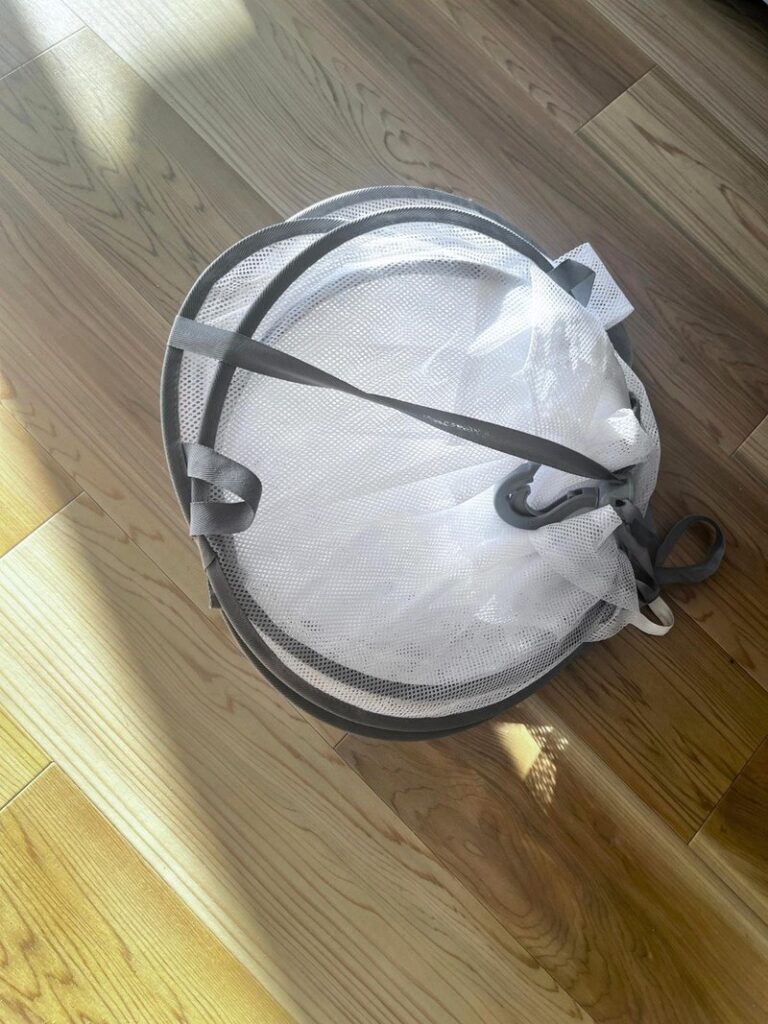 A 3-tier mesh drying rack folded down on a wooden floor