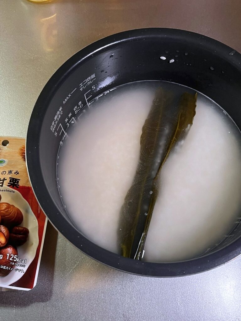 Rice, water and a piece of kombu in a rice cooker pot
