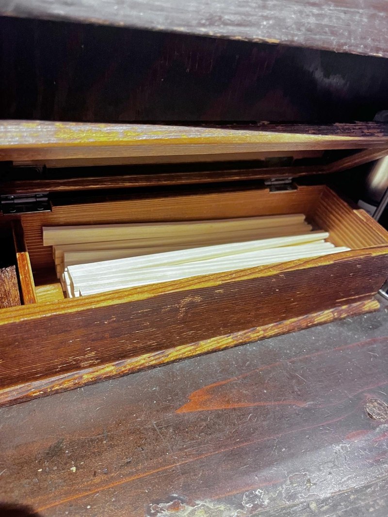 An open wooden box of disposable chopsticks on the lower level of the counter