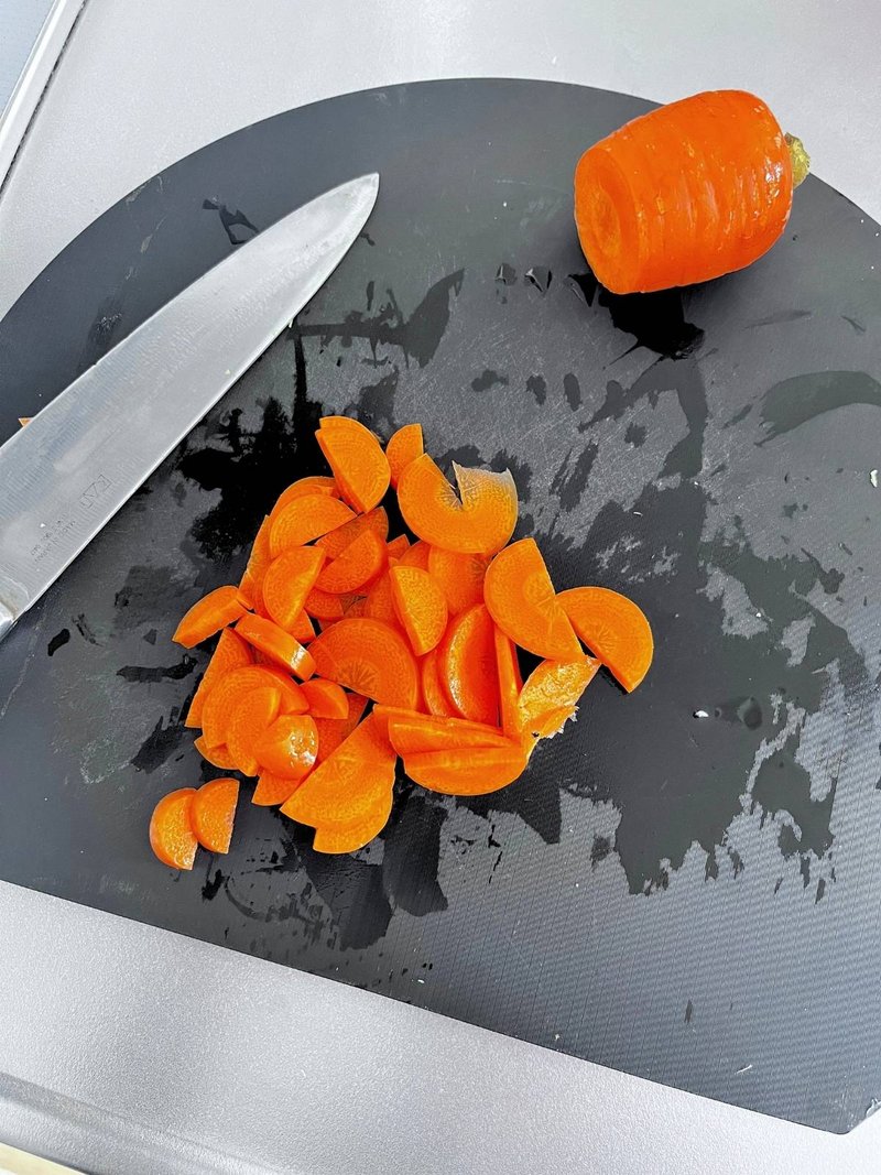 Carrot cut into half-moons on a black cutting board, with a knife
